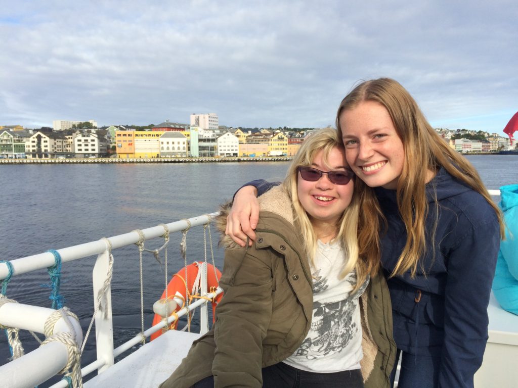 To elever sitter på en båt og holder rundt hverandre mens de smiler til kamera.